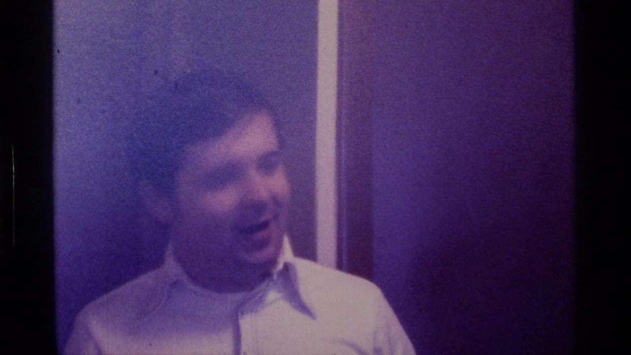 Young white man in a white dress shirt appears indoors in purple-tinted 1976 Kentucky 8mm footage, looking slightly off camera.