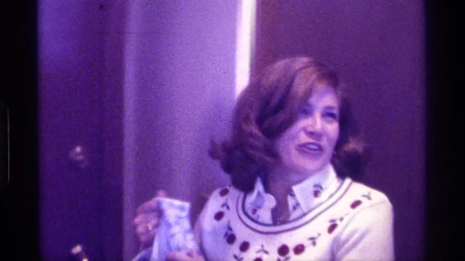 The woman smiles in a white sweater with red dot details, holding the removed plaid blazer in the Kentucky interior.