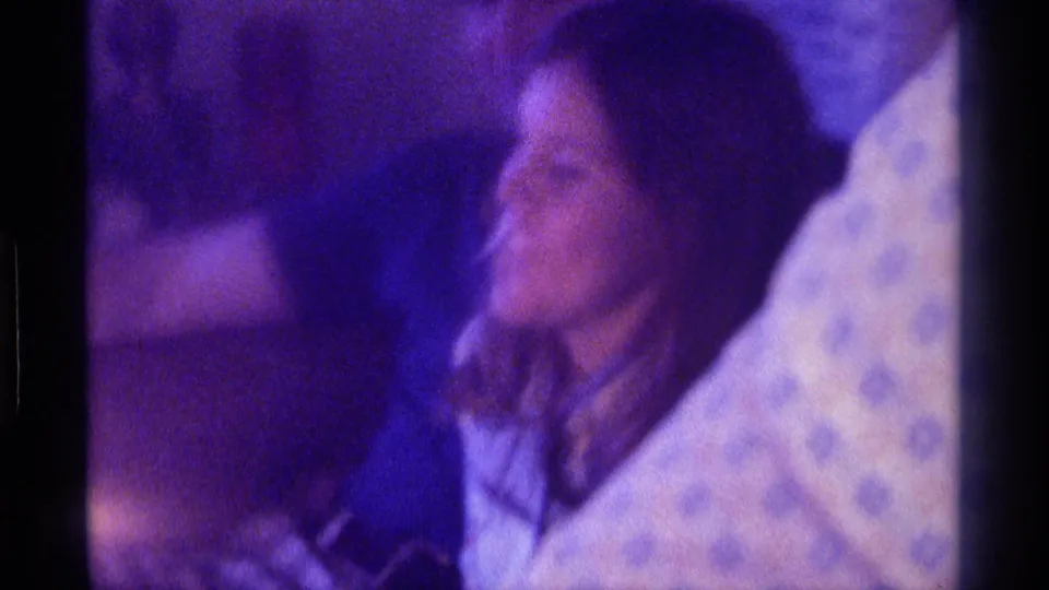 A soft-focus 8mm close view shows the smiling woman in a light top seated close to the man during the birthday scene.
