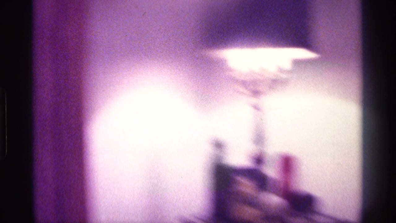 Bright table lamp beside a small object on a dim interior surface.