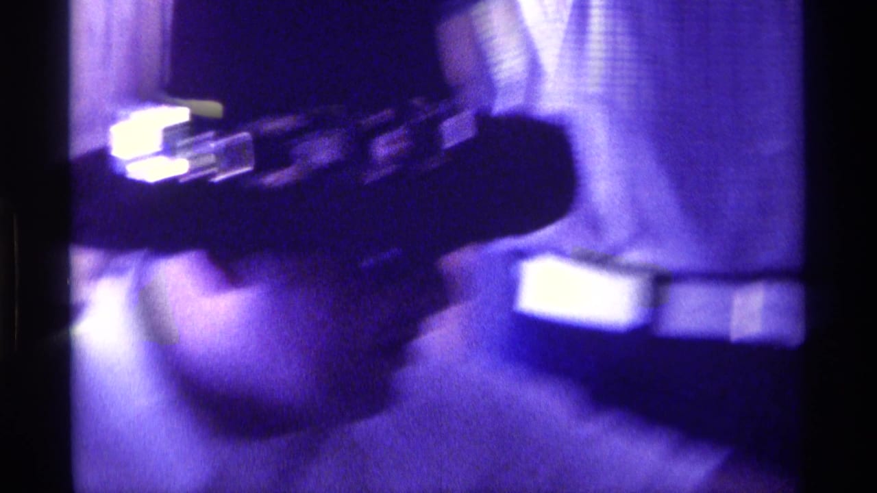1976 Kentucky 8mm frame showing a soft, purple-tinted close-up of an adult man in a dark cowboy hat near a checked curtain.
