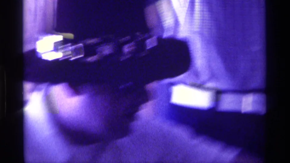 1976 Kentucky 8mm frame showing a soft, purple-tinted close-up of an adult man in a dark cowboy hat near a checked curtain.