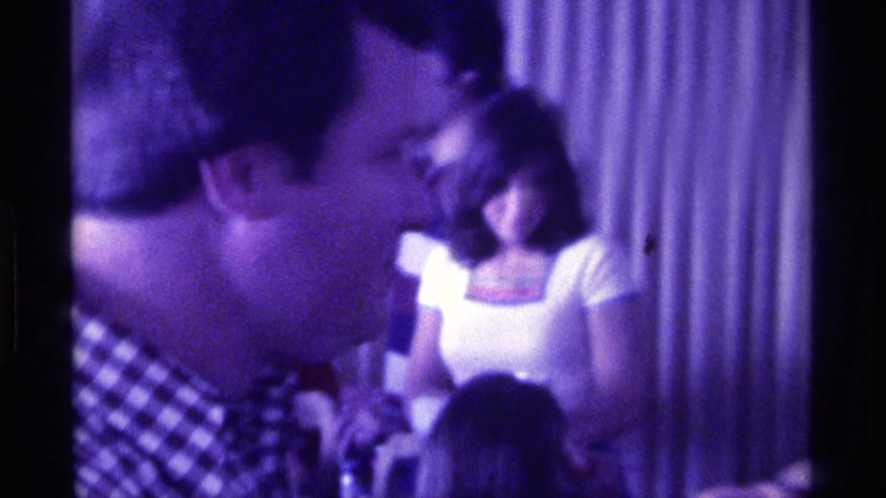 Side angle from the 1976 Kentucky party showing the man turned left, with guests and curtains softened by purple 8mm color.