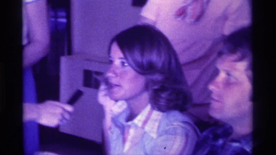 A woman with shoulder-length hair appears to answer a microphone while another woman listens beside her in the indoor Kentucky gathering.