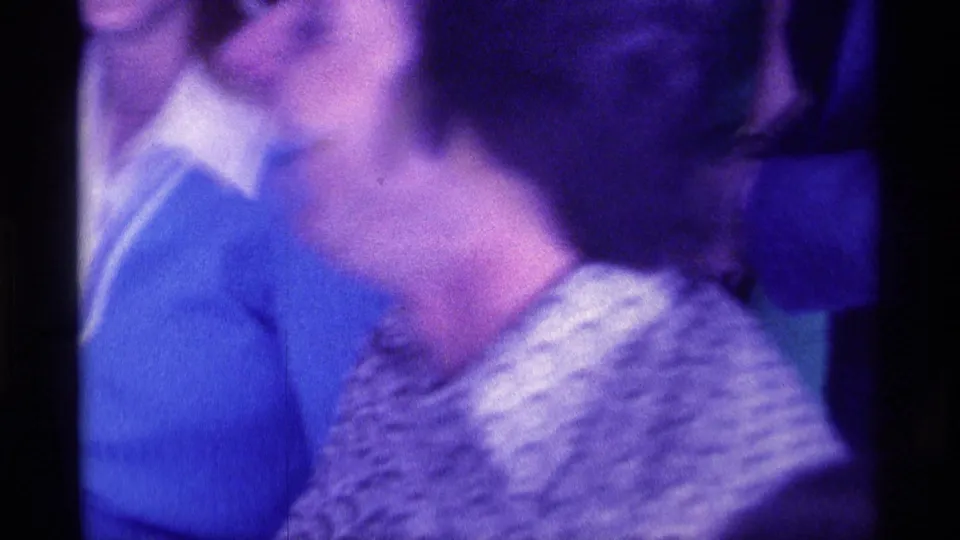1976 Kentucky home-movie frame with blurred adults moving close together during an indoor party.