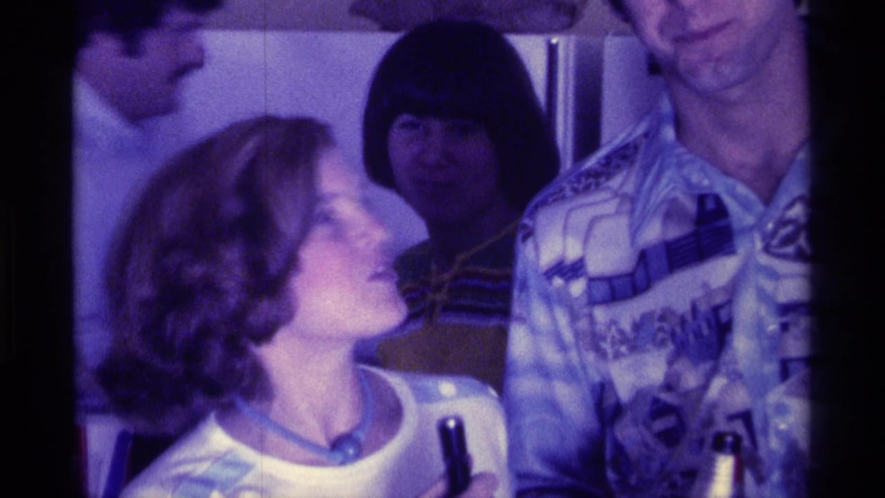 Young woman holding a microphone looks up toward a man in a patterned shirt indoors.
