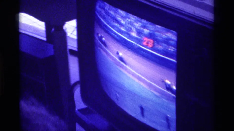 A 1976 Kentucky home-movie frame shows a television screen with horse-race footage and a red 23 visible near the track.