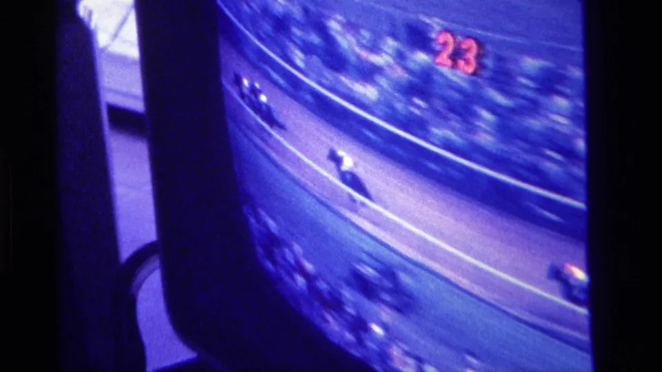 The television shows a horse race in progress, with jockeys blurred by motion and the red number 23 visible on screen.