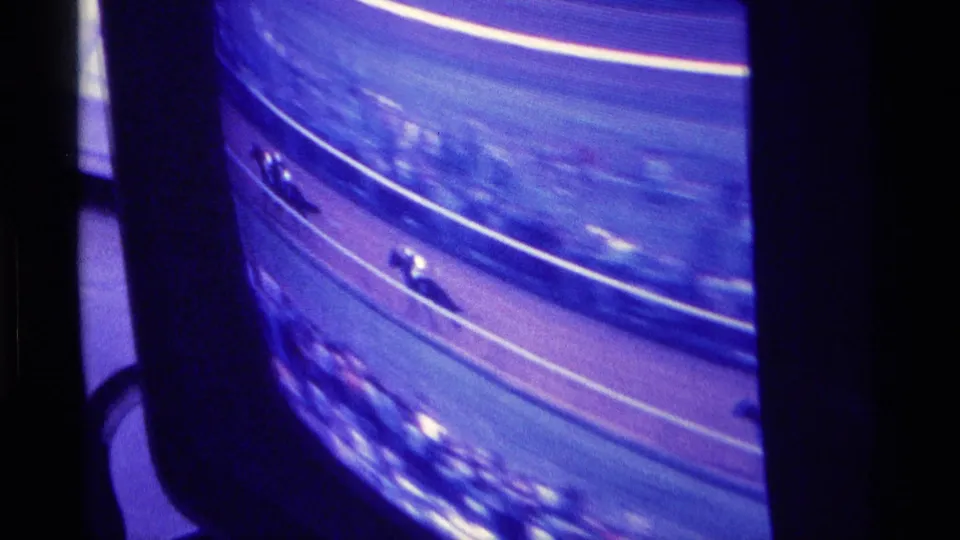 A purple-blue 8mm frame shows the televised horse race continuing around a curved track, with horses visible near the lower edge.