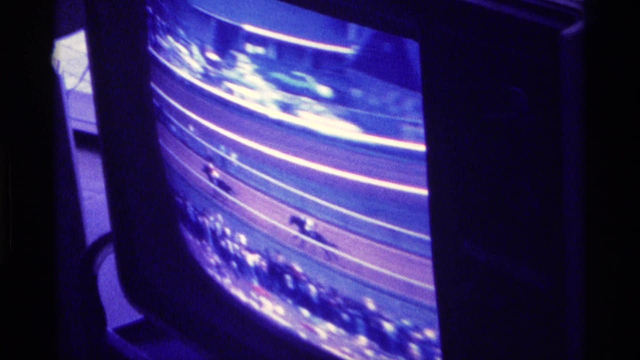 Television screen showing horses moving around a dirt racetrack bend.