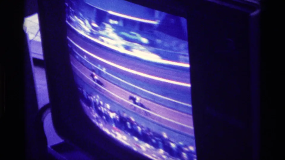 Color TV view of a horse race in Kentucky, 1976, with the dark set casing visible and spectators blurred along the track.