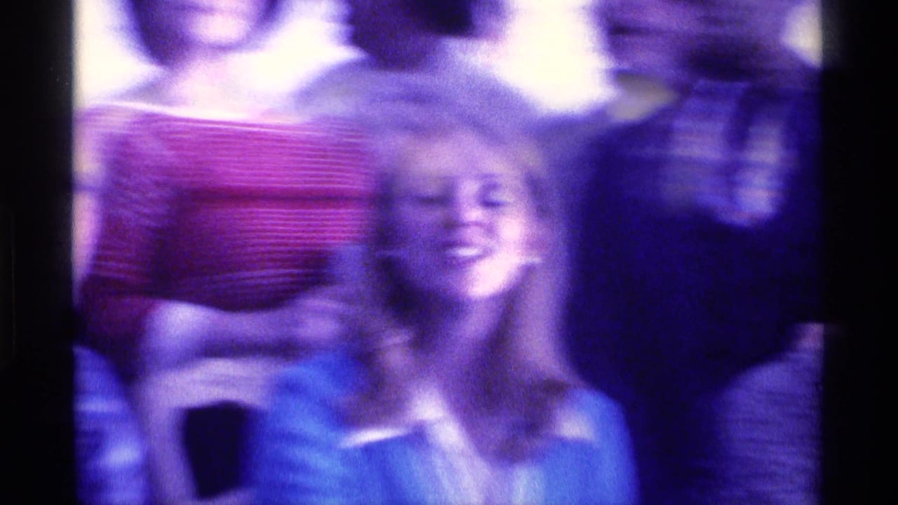 Adults gathered indoors, including a smiling woman in front of a striped shirt.