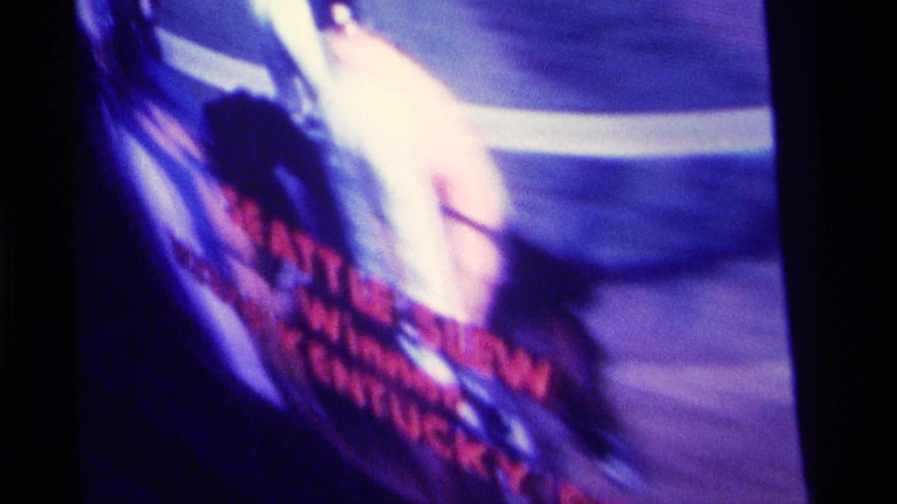 Kentucky 1976 8mm frame showing a blurred screen or television with red text and strong purple color shift.