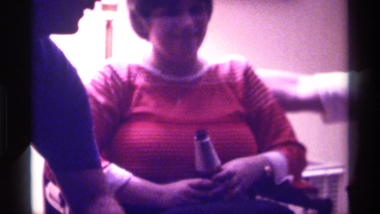 Woman in striped sweater holds a bottle as a person leans in at left.