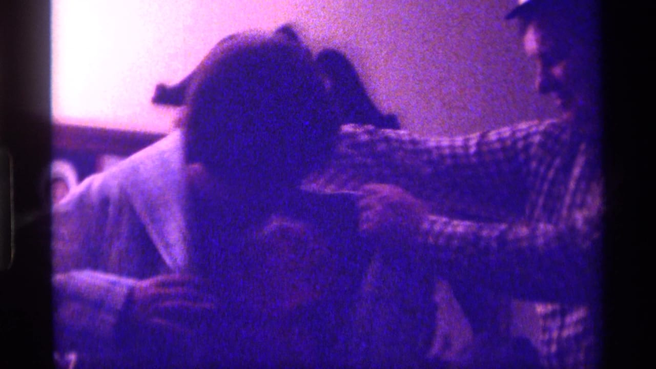 Woman bends forward in a coat as two adults help or watch from close range.