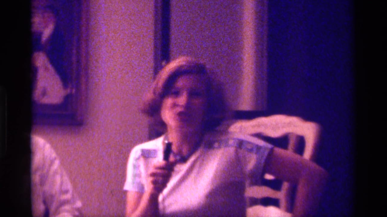 Young woman faces forward with a microphone in a dim interior.