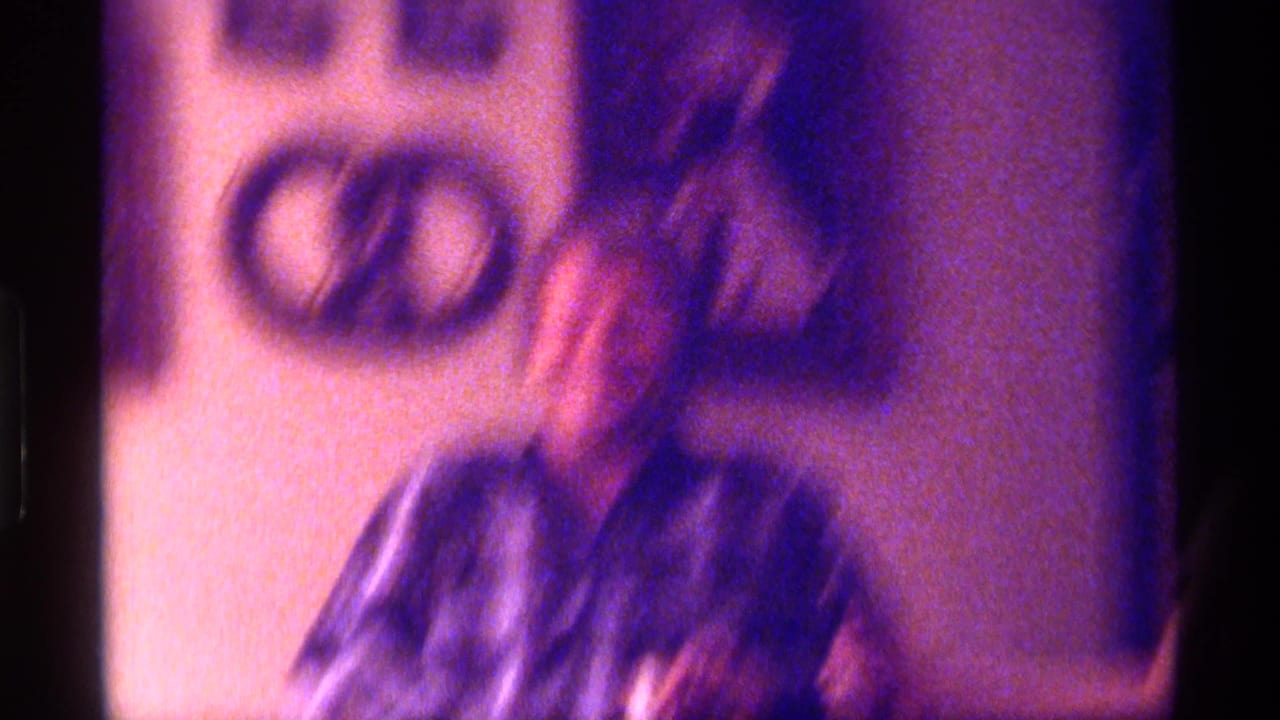 Soft, blurred view of an adult in a plaid shirt near a pretzel-shaped wall hanging.