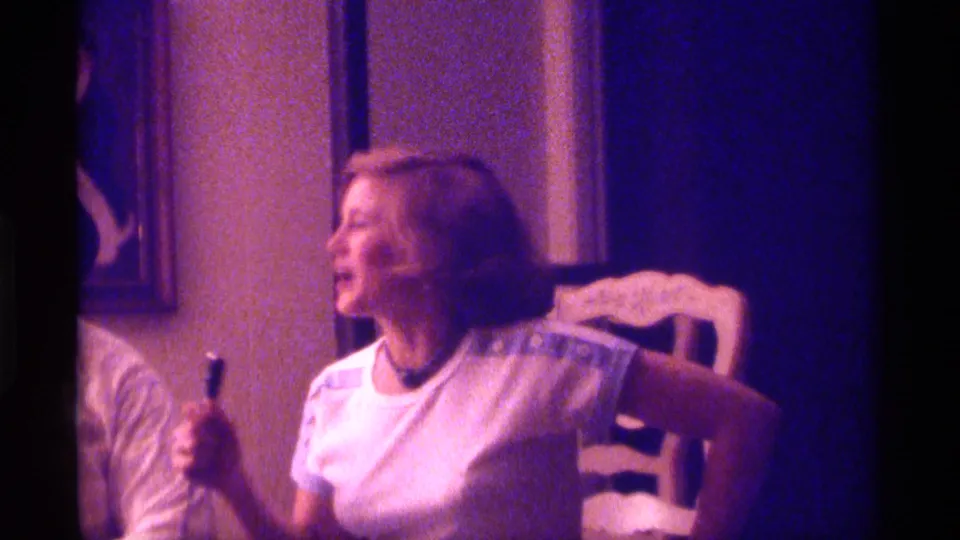 1976 Kentucky 8mm frame showing a seated woman turning to the side during an indoor family conversation.
