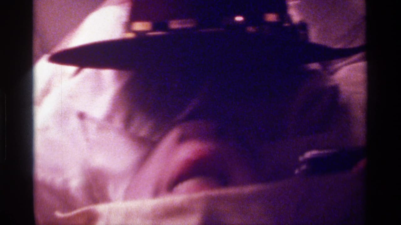 Person under a white towel and dark hat with mouth partly visible.