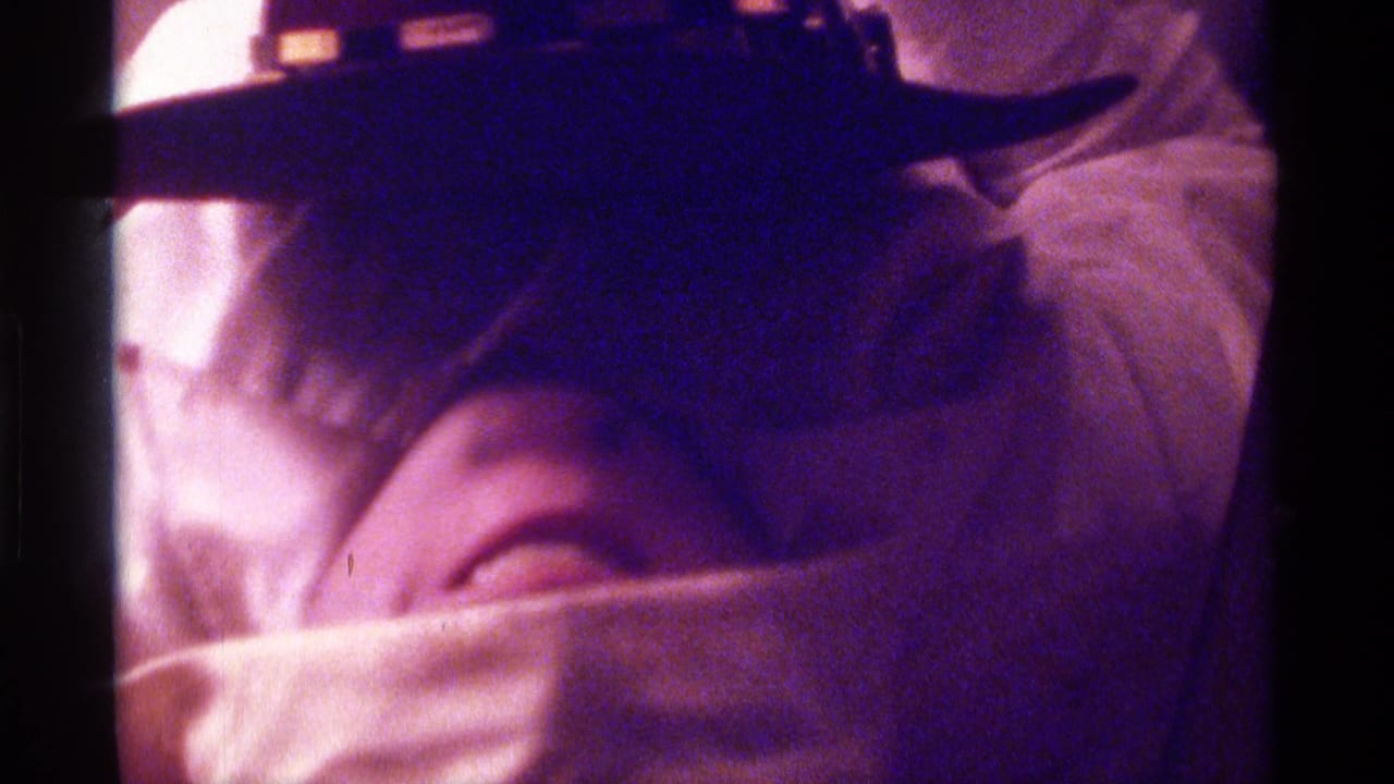Close view of a towel-covered face beneath a dark hat.