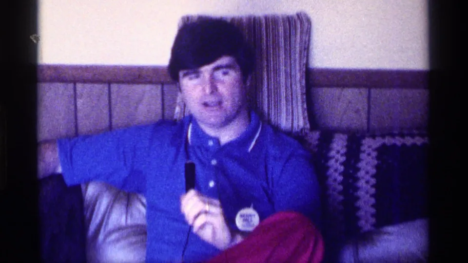 The final frame holds on the seated man with microphone in the same 1976 Kentucky living-room setting.