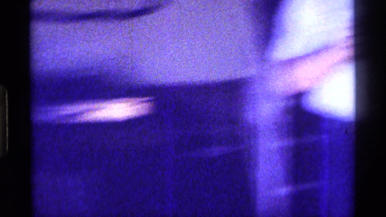 Soft, abstracted 8mm frame from the Kentucky home interior, showing blurred furniture and strong blue-purple exposure shift.