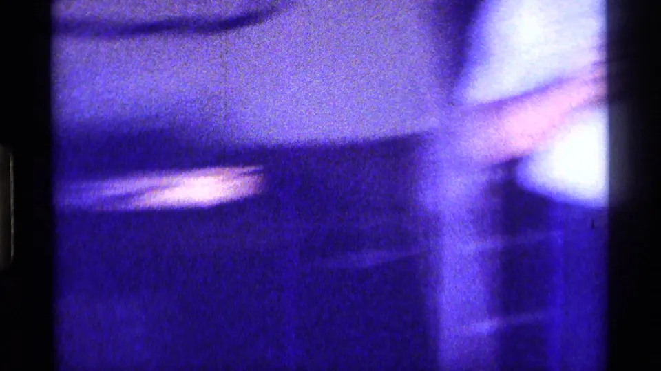 Soft, abstracted 8mm frame from the Kentucky home interior, showing blurred furniture and strong blue-purple exposure shift.