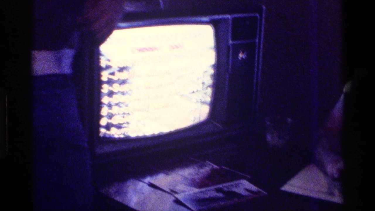 Vintage television glowing in a dark room with papers or objects below the screen.