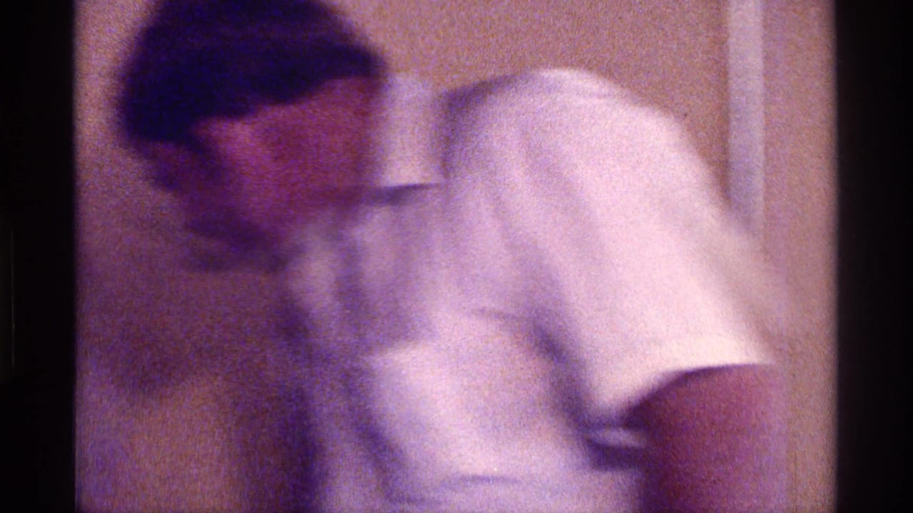 Man in a white collared shirt leaning forward indoors.
