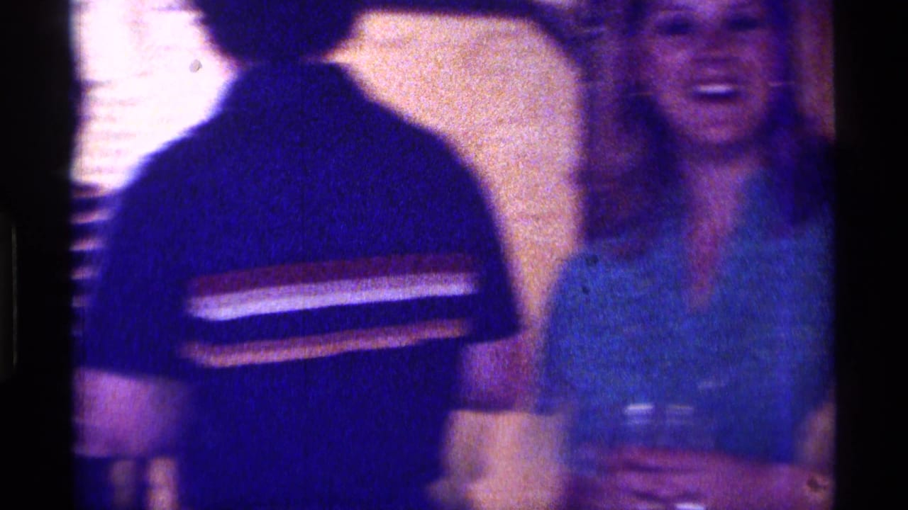 Man seen from behind near a laughing woman holding a drink indoors.