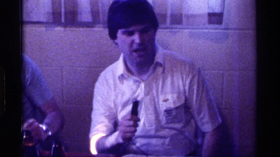 In the final frame, the man with the microphone faces forward in a dim private interior, with a second person partly visible at left.