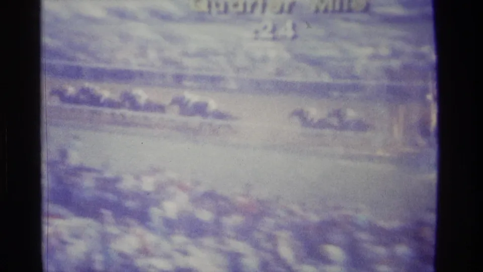 1976 Kentucky home-movie frame of a televised horse race, with horses and track rail blurred inside a dark TV border.