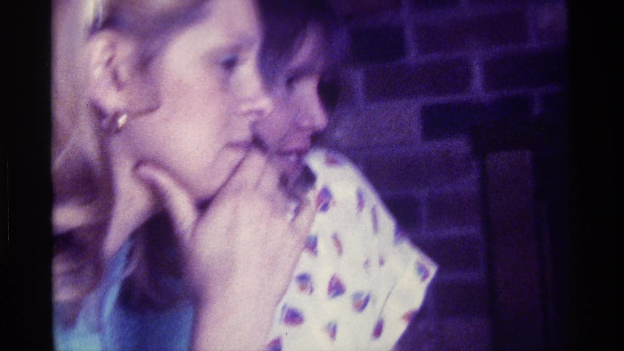 Two women in profile sit close together in a dim interior.