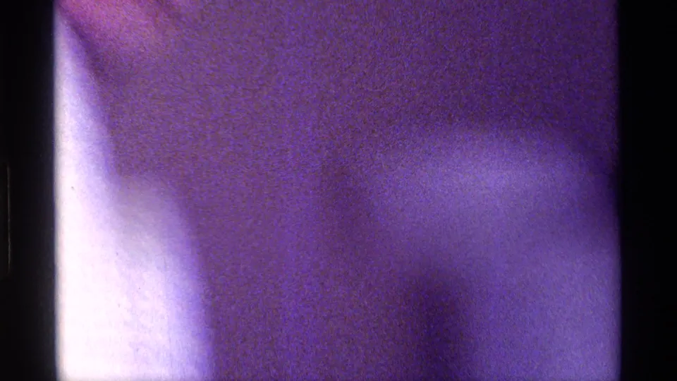 Motion-blurred 8mm frame from the Kentucky clip, with an indistinct close figure and strong purple color cast.