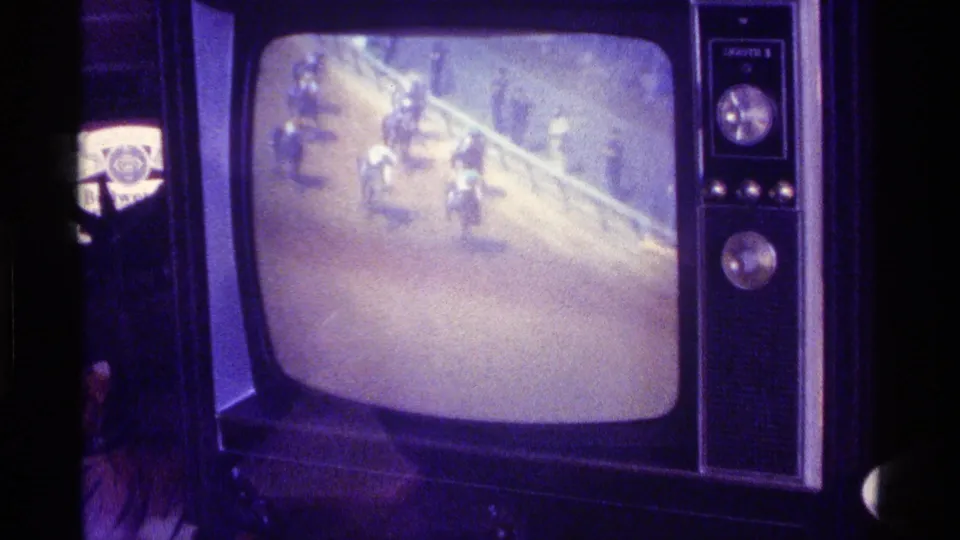 A 1976 Kentucky home-movie frame centers on a dial-controlled CRT television with a blurred horse-race broadcast on screen.