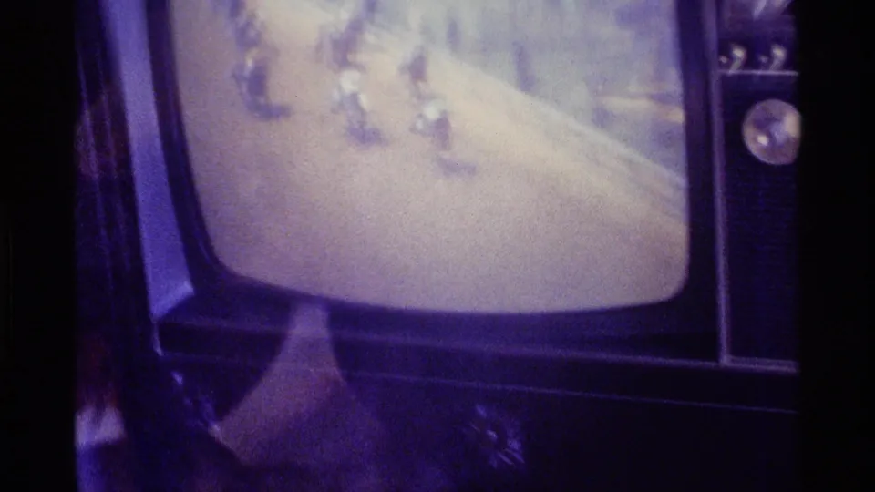 Tight 8mm frame of the living-room CRT television in Kentucky, 1976, showing horses and riders blurred across the broadcast image.