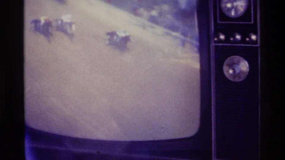 Soft 8mm frame of a vintage television in Kentucky, with side dials and pale snowy footage on the rounded screen.