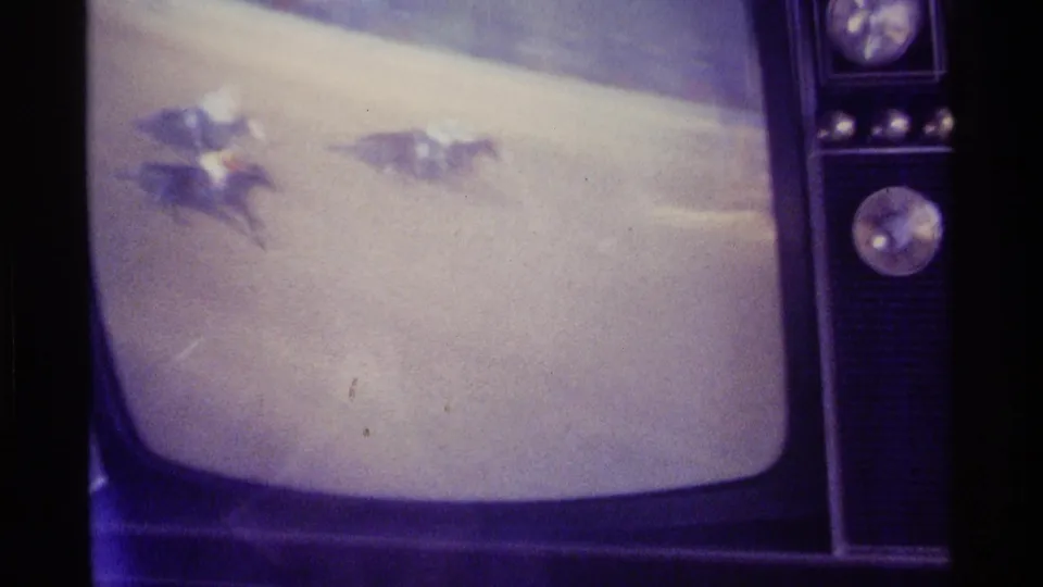 1976 Kentucky 8mm frame of a retro television displaying a horse race broadcast with analog glare and soft focus.