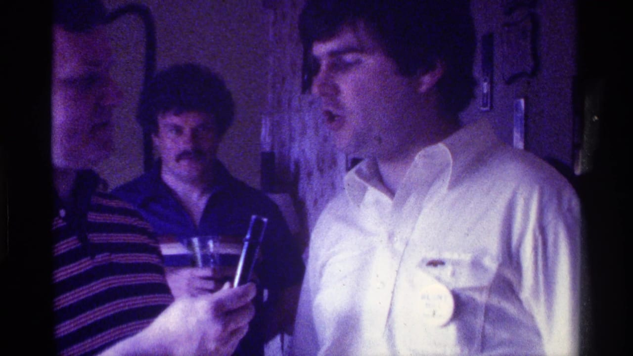 Man in white shirt continues speaking as a microphone is held near his mouth indoors.