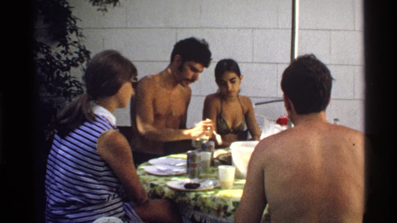 Four young adults sit around an outdoor table with food and drinks.