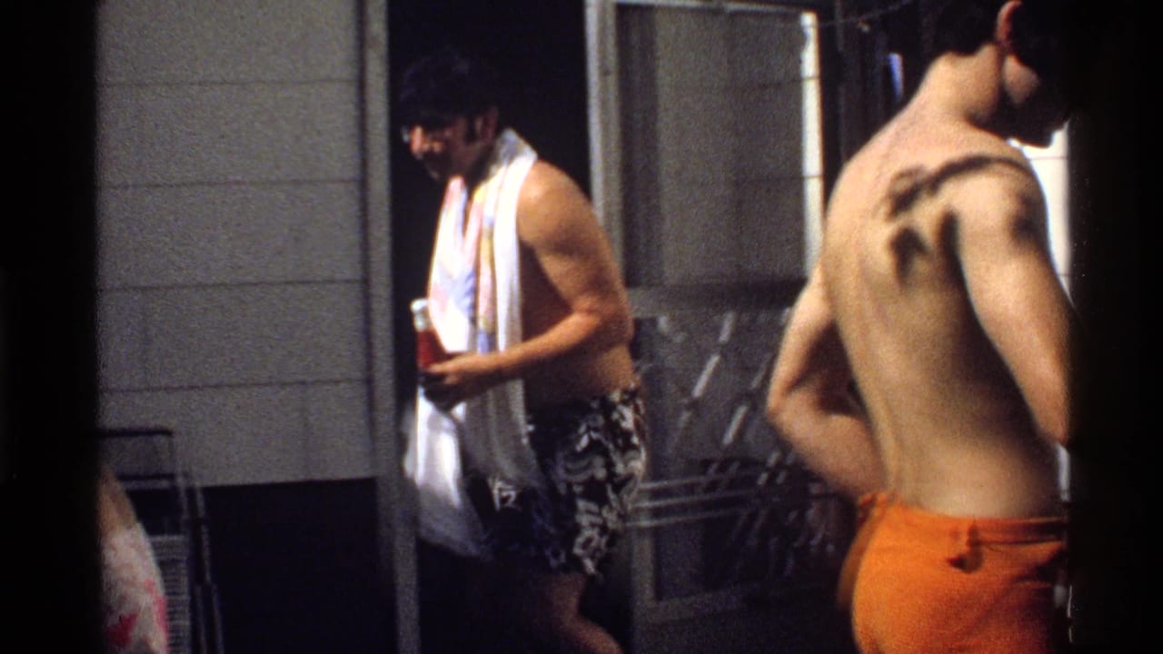 A shirtless man with a white towel around his neck walks out near patio furniture in 1978 California 8mm home-movie footage.