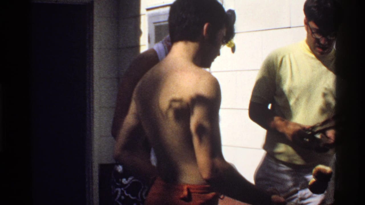 1978 California frame showing men in swimwear and casual clothing gathered in a tiled private room at a backyard party.