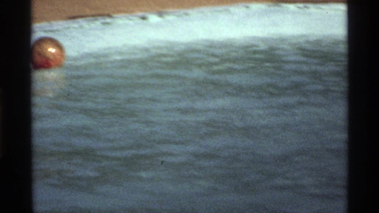 1978 California 8mm frame showing a red-orange ball floating on sunlit pool water near the pool edge.