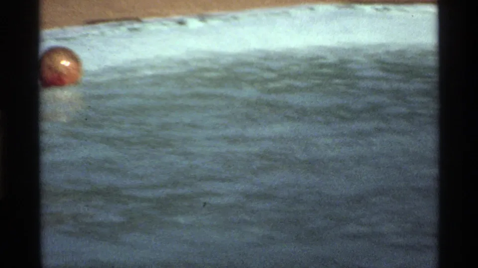 1978 California 8mm frame showing a red-orange ball floating on sunlit pool water near the pool edge.