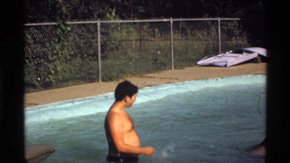 1978 California 8mm pool scene with an adult man standing in the water as a small splash appears near his hand.