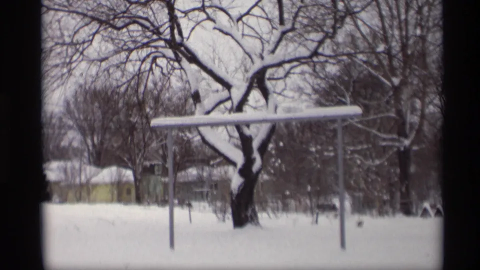1966 Madison winter yard frame showing deep snow, a horizontal yard bar, bare trees, and small background structures.