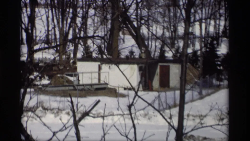 1966 Madison winter frame with a small white shed, bare trees, snow cover, and foreground branches.