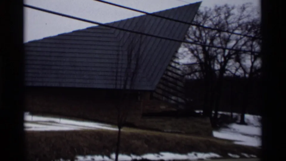 Exterior view in Madison, Wisconsin metadata context, showing a modernist building with a steep angled roof beside patchy snow and bare trees.
