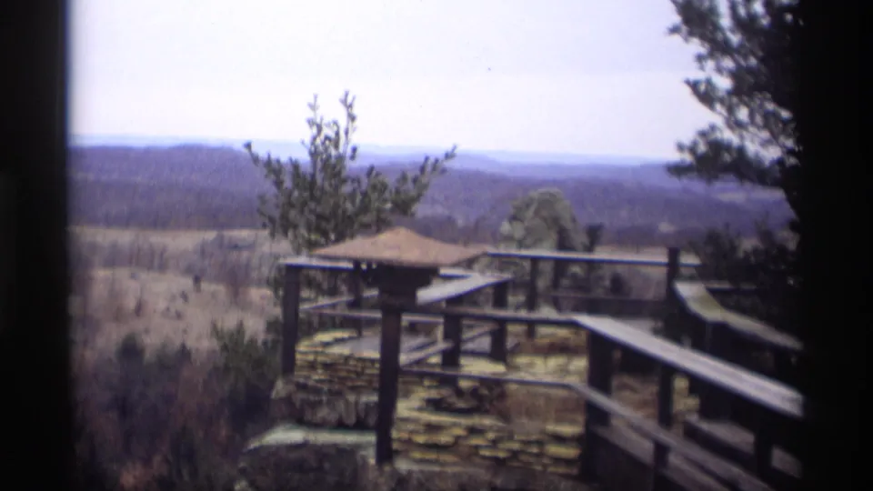 1966 8mm view in Madison, Wisconsin, showing a wooden walkway and stone overlook above a distant wooded landscape.