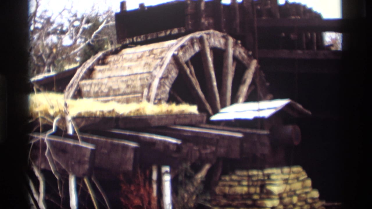 Madison, Wisconsin 1966 footage holds on a weathered mill wheel, rough timber, stone base, and winter-bare trees.